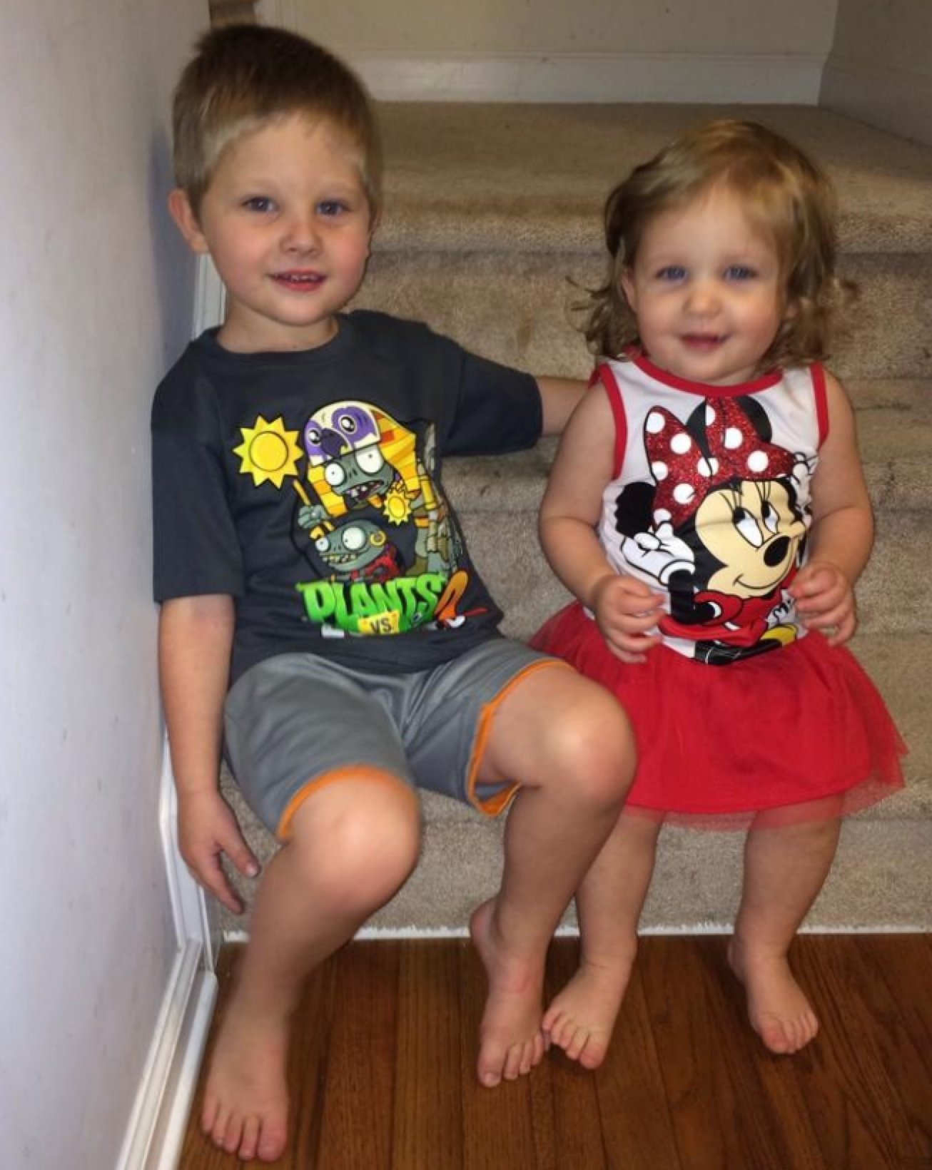 Two young siblings sitting together on a staircase.