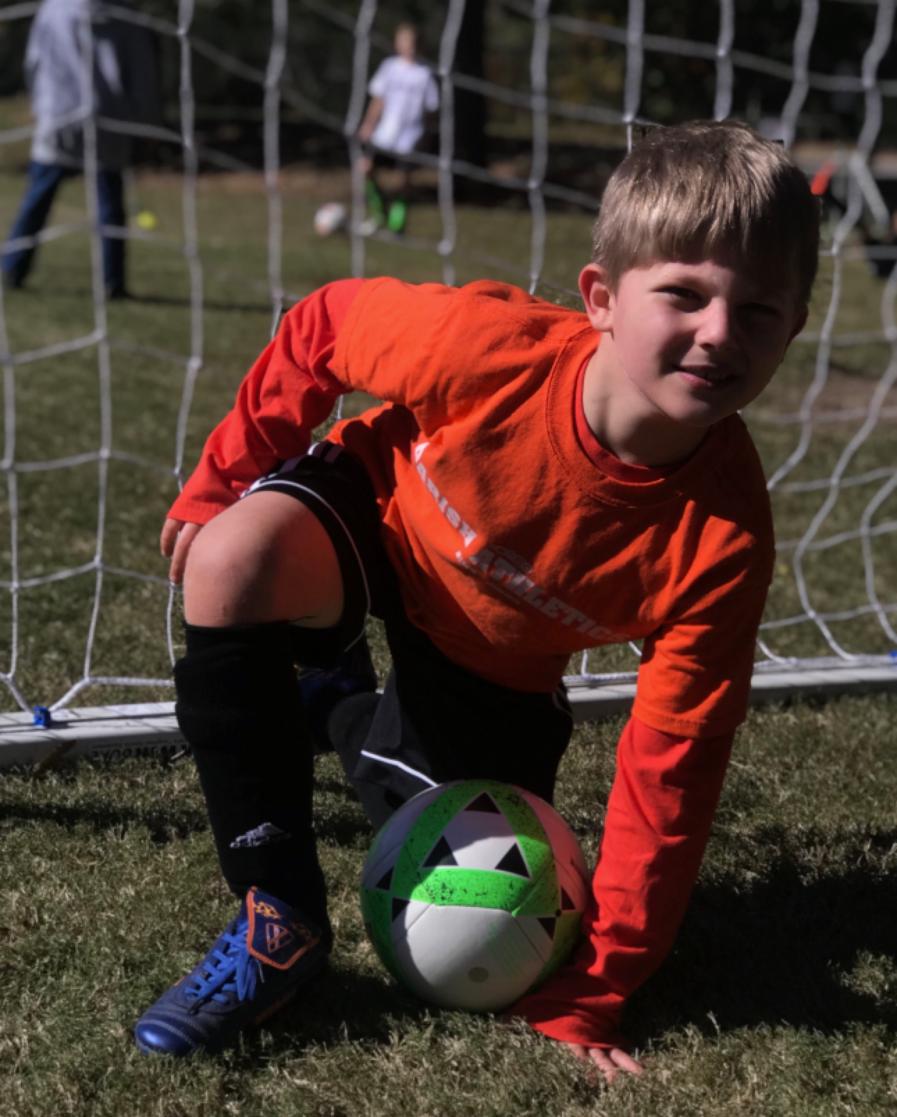 Trey as a young child, kneeling on a soccer field by the goal.